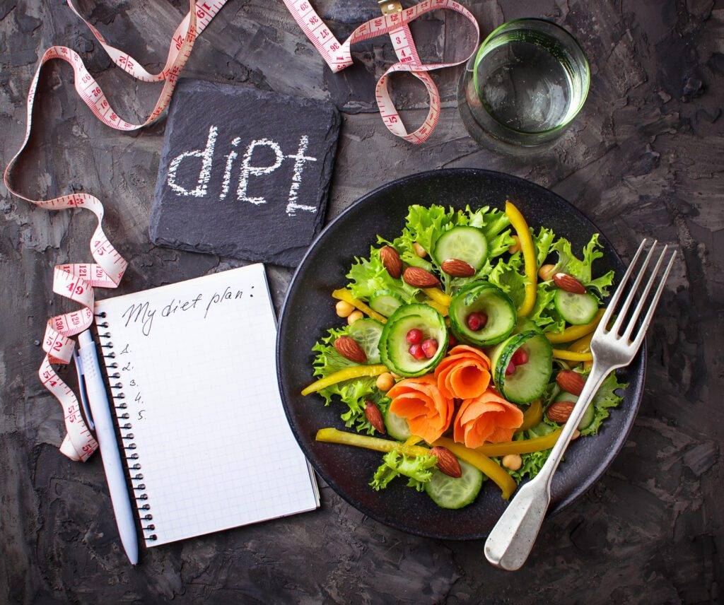 Healthy vegetable salad, glass of water and tape measure. Diet concept. 