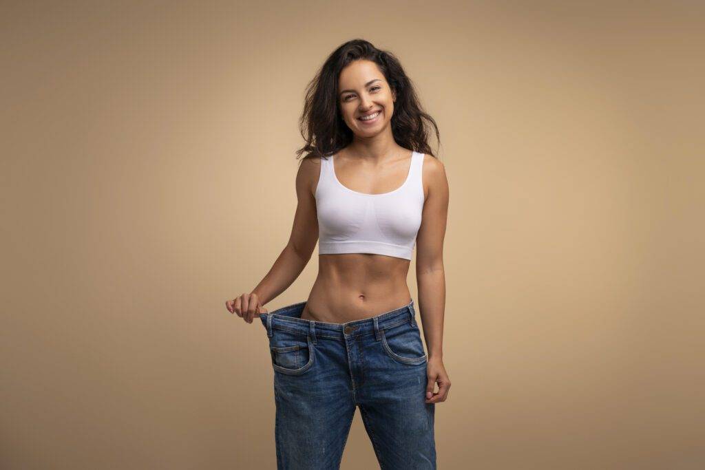 showing results of diet, exercise and combination of therapies demonstrating loose in waist, beige studio background, slimming concept, copy space